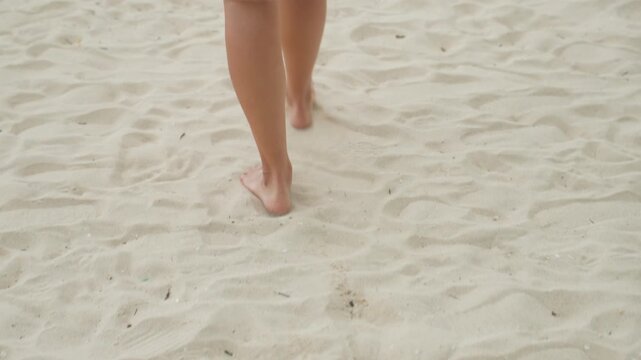 Solo woman on sandy beach. Female adventurer walking unshod along secluded coastal sands at dawn. Woman in bare feet exploring remote island coastlines during peaceful morning hours