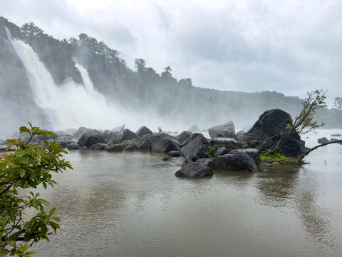 Powerful Athirappilly Falls surrounded by lush forest and boulders in Thrissur, Kerala.
