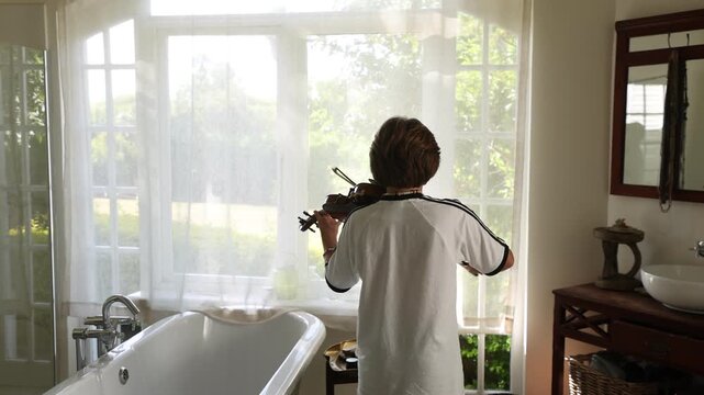 12 year old boy playing violin in bathroom