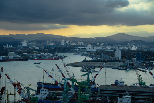 Ulsan Industrial Complex Skyline. Oil Refineries, Petrochemical Plants, Shipyard Cranes and Taehwa River at Sunset with Dramatic Clouds