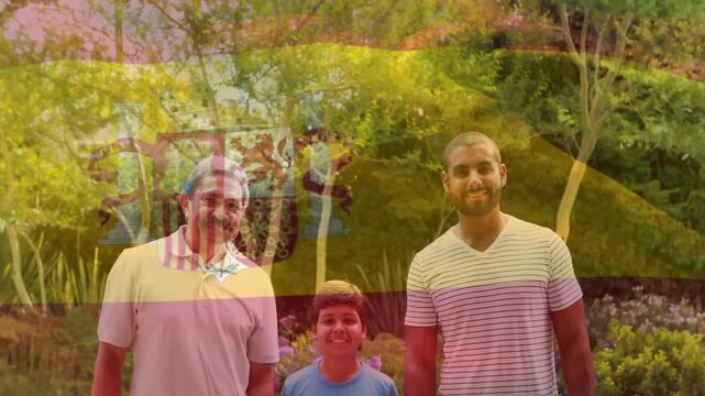Animation of flag of spain over father with adult son and grandson in park