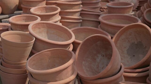 A close up shot of various handmade terracotta clay pots and planters stacked at an outdoor street vendor market in India. Ideal for gardening and pottery craft themes.