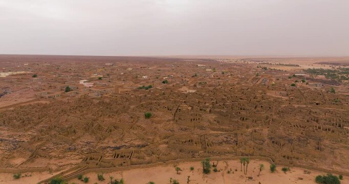 Ancient Stone Ruins Of Ouadane, Mauritania, With Weathered Remains Of The Old City Against Desert Horizon. aerial approach