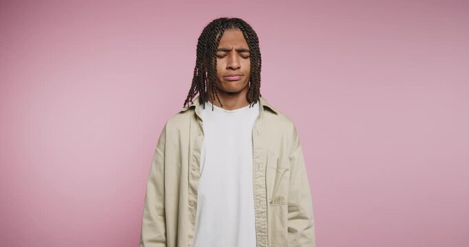 Young man with braids conveys deep emotions in a creative portrait shoot against a pink backdrop