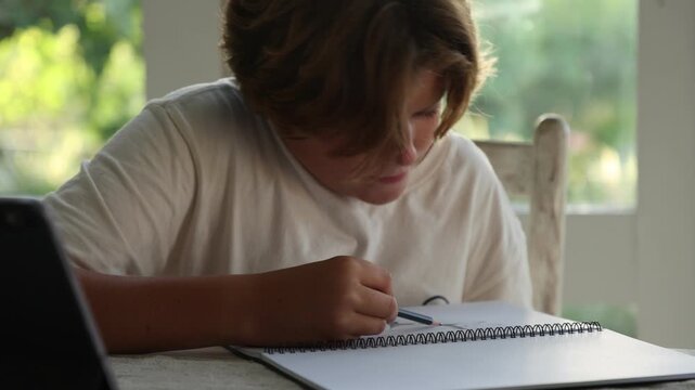 12 year old boy doing a pencil drawing in his living room