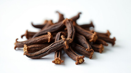 Obraz premium Dried whole cloves piled together on white background. These aromatic spice buds offer rich flavor for cooking and baking. Useful for food blogs, recipe sites, and culinary content.