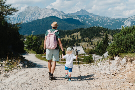 Father and young son walking down a rocky mountain trail enjoying an active family vacation.