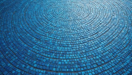 Fototapeta premium Blue mosaic pavement shows circular pattern. Small square tiles form concentric rings, creating a textured floor surface. Geometric design alternates light and dark blue.