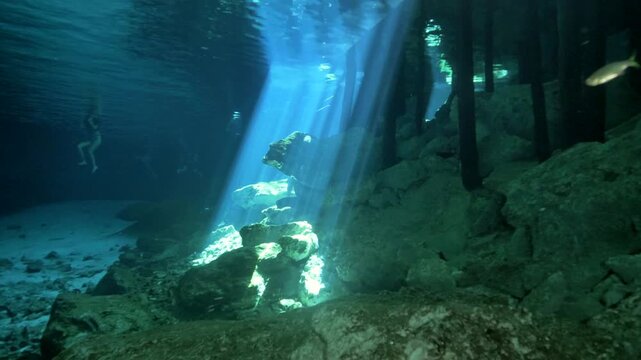 Surface ripples create shifting light beams across rocky cave bottom in Cenote Dos Ojos, Quintana Roo, Mexico