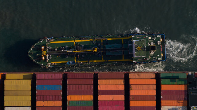 Aerial view of a service vessel alongside a large container ship with colorful stacked cargo at Kwai Tsing Container Terminal V, Hong Kong, New Territories, Hong Kong.