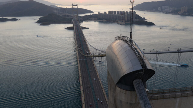Aerial view of the Tsing Ma Bridge tower and suspension cables spanning the sea with traffic and distant islands during twilight in Hong Kong, China.