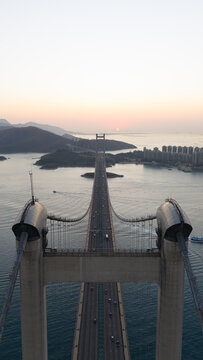 Aerial view of the Tsing Ma Bridge with traffic crossing over the water during a soft sunset over the islands Hong Kong, China.