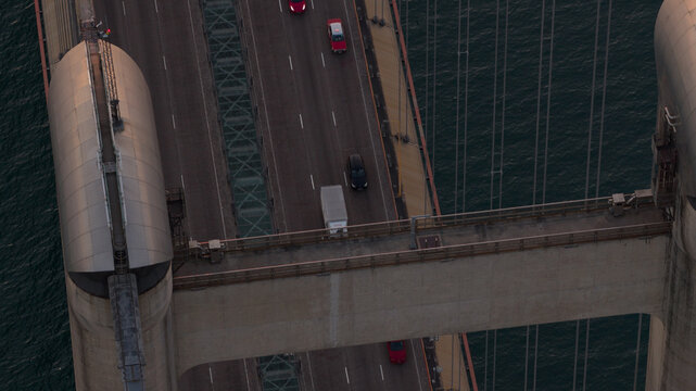 Aerial view of the Tsing Ma Bridge with vehicles driving across the suspension structure over the dark sea in Hong Kong, China.