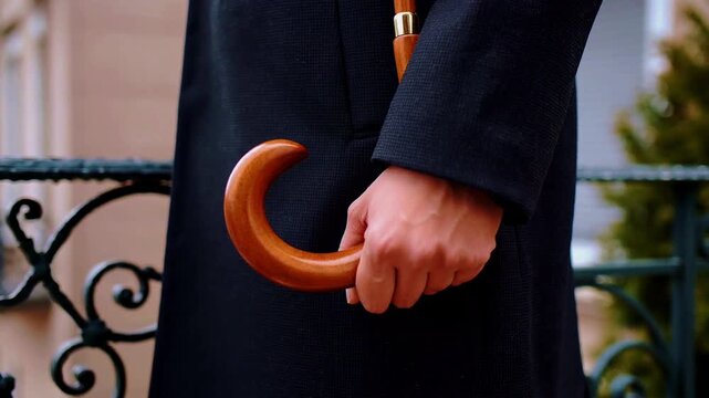 Hand holding a wooden umbrella handle with a black coat image photo