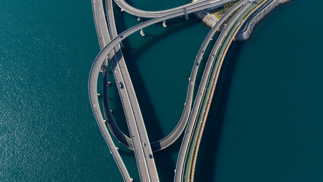 Aerial view of the Cross Bay Link bridge interchange with curved roads over deep blue water in New Territories, Hong Kong.