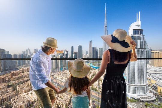 A tourist family enjoys the panoramic view over the skyline of downtown Dubai, UAE, from their balcony