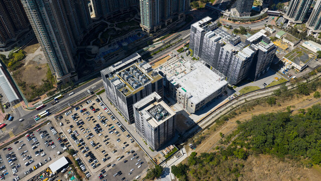 Aerial view of Data Center complex with modern industrial buildings, large parking lot, and surrounding residential skyscrapers in Tseung Kwan O, New Territories, Hong Kong.