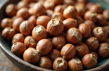 Fototapeta premium A bowl filled with raw hazelnuts. The brown nuts are piled high, showing their textured shells. These seeds offer natural ingredients for healthy eating and snacks.