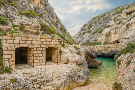 Wied il-Ghasri valley in Malta on a sunny day, featuring a narrow rocky gorge, turquoise water, and peaceful Mediterranean scenery surrounded by natural cliffs.