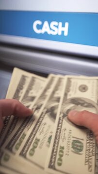 A man withdraws dollar cash from an ATM.