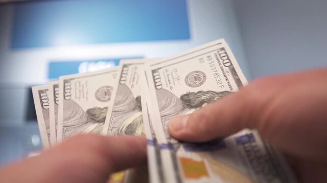 A man withdraws dollar cash from an ATM.