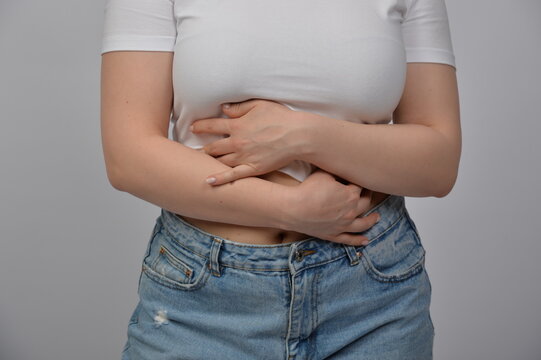 Frau h&auml;lt Bauch, Thema V&ouml;llegef&uuml;hl, Menstruationsbeschwerden oder Schwangerschaft, Fokus auf Bauchschmerzen, Gesundheit und K&ouml;rpergef&uuml;hl mit Copyspace
