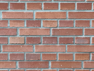 Obraz premium Brick wall with a pattern of alternating red and brown bricks during daylight