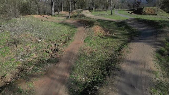 pump track or dirt jump park designed for mountain bikes MTB or BMX. trails rollers humps and berms banked corners goal is navigate track without pedaling, pumping motion pushing down into the dips 