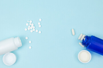 Top view of two bottles with scattered pills on a light blue background. Concept of medical treatment, pharmacy, medication management, and available copy space for text or message © Answer 7