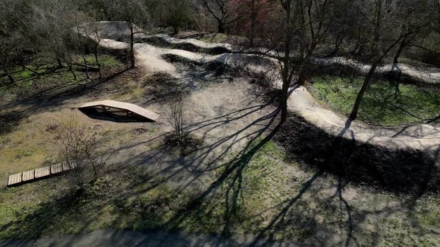 pump track or dirt jump park designed for mountain bikes MTB or BMX. trails rollers humps and berms banked corners goal is navigate track without pedaling, pumping motion pushing down into the dips 