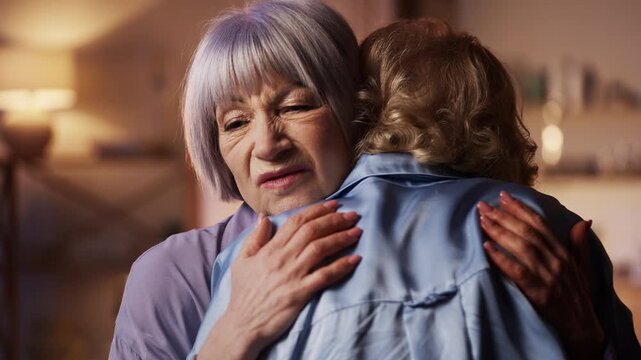 Senior woman frowning while hugging female friend, fake friendship concept