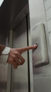 Vertical shot of young male office worker with dreaded hair wearing suit pressing elevator button and entering cabin in modern business center