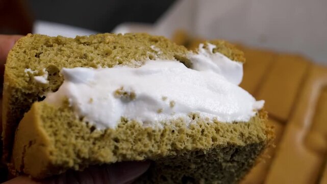 A close-up shot of a hand holding a delicious slice of moist, spiced gluten-free pumpkin cake with a thick layer of white cream cheese frosting. Perfect for fall baking, holiday desserts, and healthy 