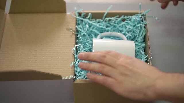White mug. Cardboard box. Parcel. Slow motion video. High quality 4k footage