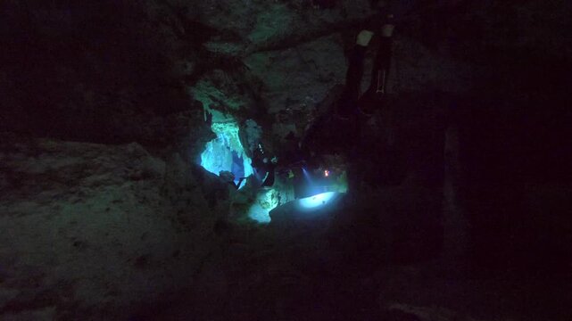 Diver illuminates surroundings with light beam while moving in dark cavern water in Cenote Dos Ojos, Quintana Roo, Mexico