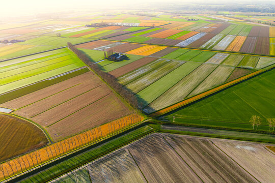 Aerial view of a patchwork of colorful agricultural fields, a small farmstead, and drainage canals in Mont Saint-Michel, Normandy, France.