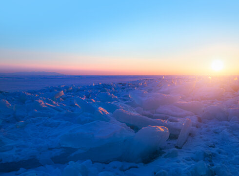 Beautiful winter landscape of frozen Lake Baikal at sunrise - Snowy ice hummocks with transparent blue piles of ice - Lake Baikal, Irkutsk region, Russia