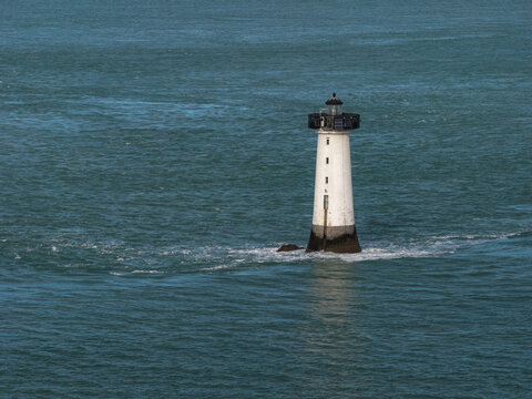 Aerial view of the white Phare de la Pierre-de-Herpin lighthouse surrounded by the turquoise waters of the sea near Cancale, Bretagne, France.