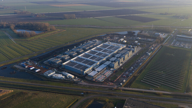 Aerial view of Datacenter Winschoten featuring massive industrial halls, cooling units, and solar panels surrounded by green agricultural fields in Winschoten, Netherlands.