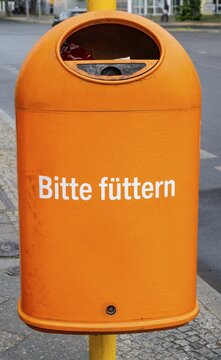 Funny orange garbage can with the inscription Bitte f&uuml;tern, Berlin, Germany