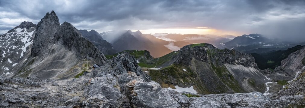 Summit of the Westliche T&ouml;rlspitze, in the background cloudy mountains at sunset with dramatic light, craggy rocky summit of the Partenkirchener Dreitorspitze, in the background Reintal and Zugspitzplatt, Wetterstein Mountains, Garmisch Partenkirchen, Bavaria, Germany