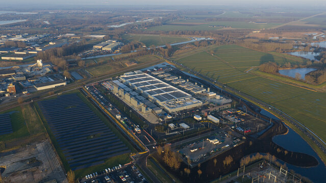 Aerial view of the Datacenter Winschoten facility featuring extensive solar panel arrays and industrial cooling systems surrounded by green fields and canals Winschoten, Groningen, Netherlands.
