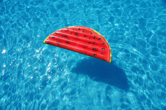 Swimming pool with floating mattress as a colorful watermelon. Having fun on vacation at the hotel pool. Colorful vacation concept.