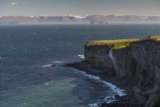 Waterfall falls over cliff and is blown away by wind, in the background Saga Island Drangey, Skagi Peninsula, Skagafj&ouml;r&eth;ur, Nor&eth;urland vestra, Iceland