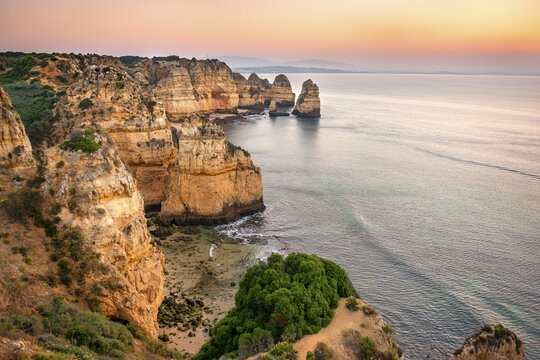 Rugged rocky coast with cliffs of sandstone, rock formations in the sea, Ponta da Piedade, dawn at sunrise, Algarve, Lagos, Portugal