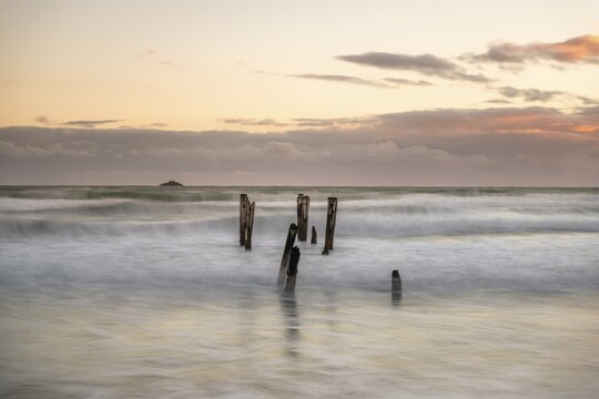Old broken jetty, post in water on beach, evening mood, St. Clair, Dunedin, South Island, New Zealand