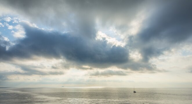 Sailing boat in the sea, against dramatic clouds, France
