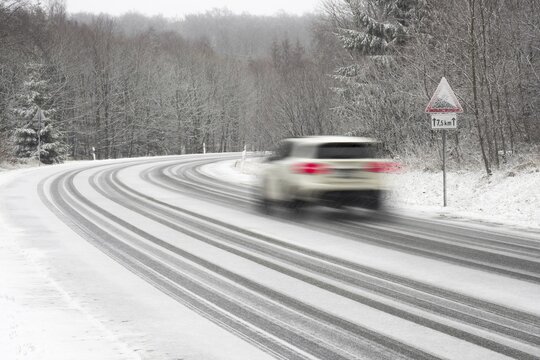 Car driving on snow-covered road, Warning sign, gradient, Hesse, Germany