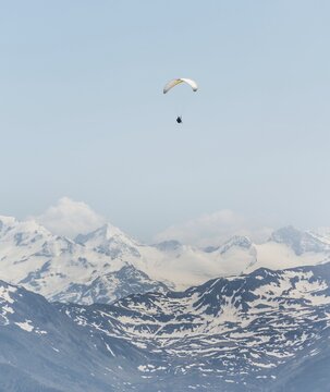 Paraglider against a blue sky, snow-capped peaks of the Alps at the back