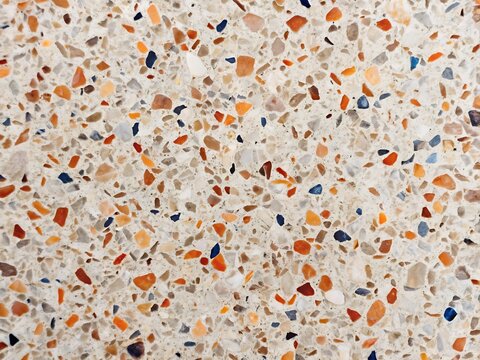 Detailed view of a beige terrazzo surface with scattered orange and blue chips floor